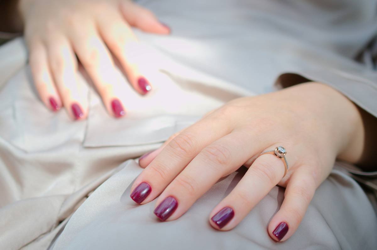 Close-up of hands applying simple nail stencil art with clean geometric patterns