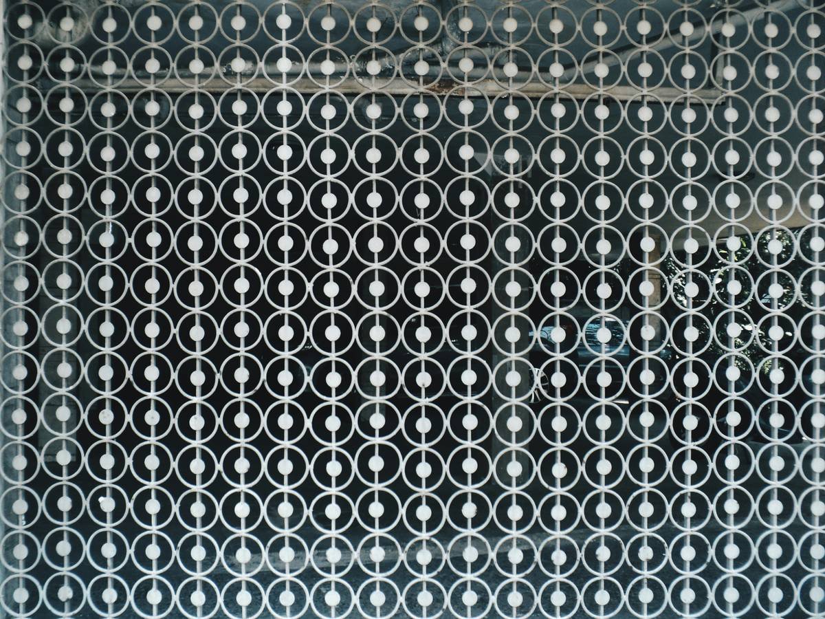 Close-up of hand-cut unique nail stencil pattern on mylar film being aligned on natural nail
